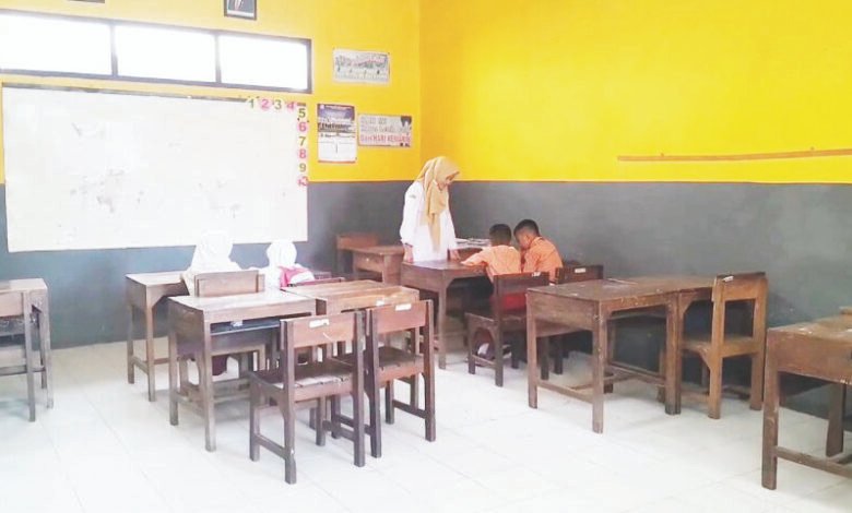 Seorang guru di salah satu SD Negeri di Kabupaten Demak menemani siswanya belajar pada awal masa sekolah. Menunjukkan bahwa SDN di Demak kekurangan siswa baru. (Lingkartv.com)
